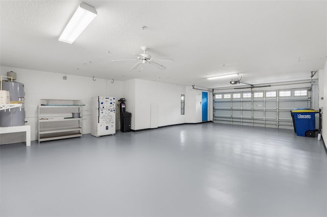garage with electric water heater, a garage door opener, ceiling fan, and freestanding refrigerator