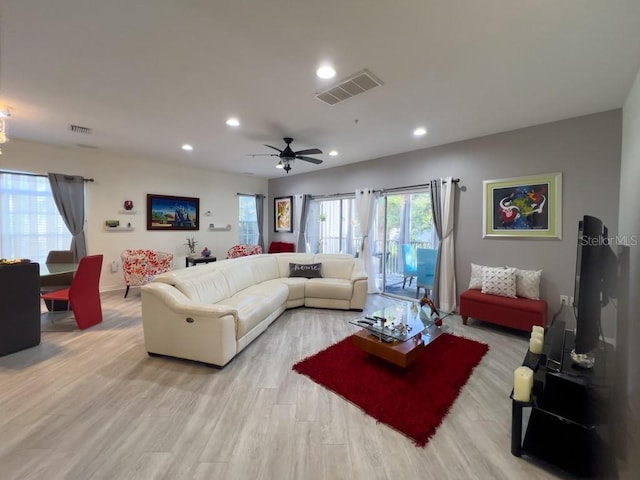 living room with recessed lighting, healthy amount of natural light, light wood-style flooring, and baseboards