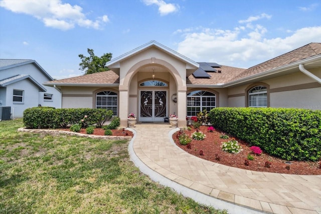 3773 E Lake Todd Dr, Hernando, FL 34442 - doorway to property with stucco siding, solar panels, a shingled roof, and a yard