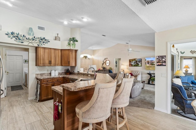 3773 E Lake Todd Dr, Hernando, FL 34442 - kitchen with a sink, brown cabinets, open floor plan, a breakfast bar, and a peninsula