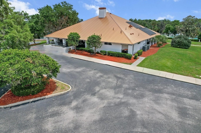 3773 E Lake Todd Dr, Hernando, FL 34442 - view of home's exterior with solar panels, central AC unit, a lawn, a chimney, and metal roof