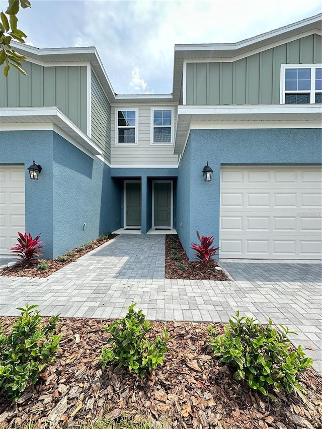 5232 Luisa Ct, Saint Cloud, FL 34771 - view of front facade featuring board and batten siding, stucco siding, a garage, and driveway