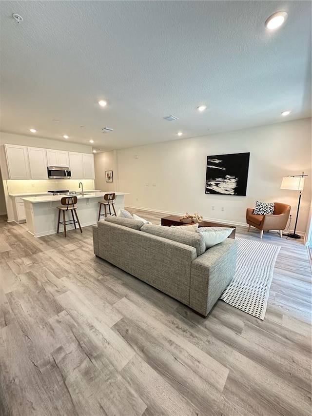 5232 Luisa Ct, Saint Cloud, FL 34771 - living room with light wood-style flooring, recessed lighting, a textured ceiling, and baseboards
