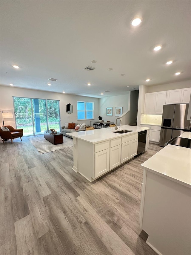 5232 Luisa Ct, Saint Cloud, FL 34771 - kitchen with stainless steel fridge, a sink, black dishwasher, open floor plan, and light wood-style floors