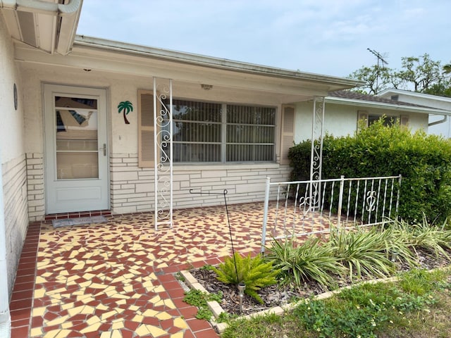 doorway to property with stucco siding and brick siding