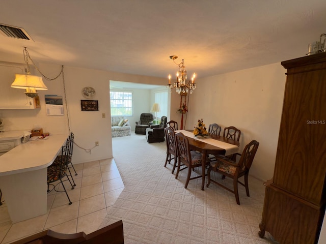 dining area with a chandelier, light tile patterned floors, and light colored carpet