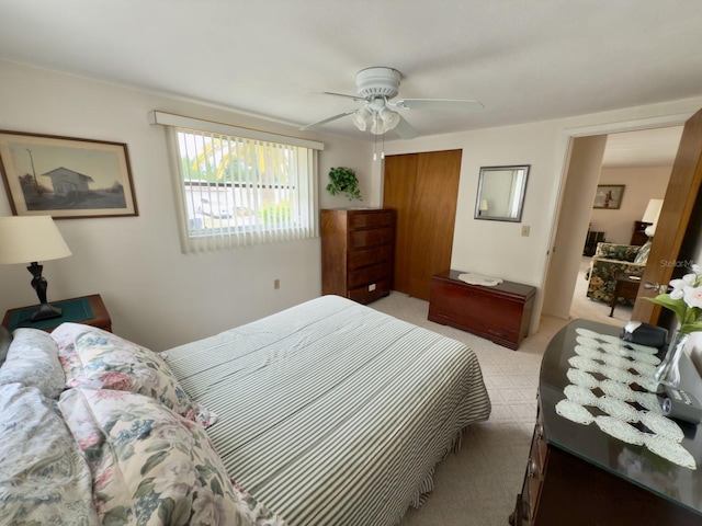 bedroom with light carpet, a closet, and a ceiling fan