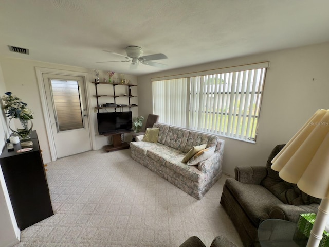 living area with ceiling fan, plenty of natural light, and carpet