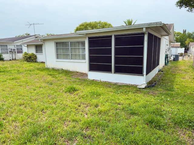 view of home's exterior featuring a lawn, a sunroom, cooling unit, and stucco siding