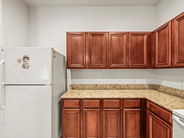3885 Crossline Dr, Spring Hill, FL 34609 - kitchen featuring freestanding refrigerator, light stone countertops, and reddish brown cabinets
