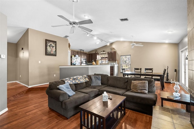 living area featuring ceiling fan, lofted ceiling, wood finished floors, and baseboards