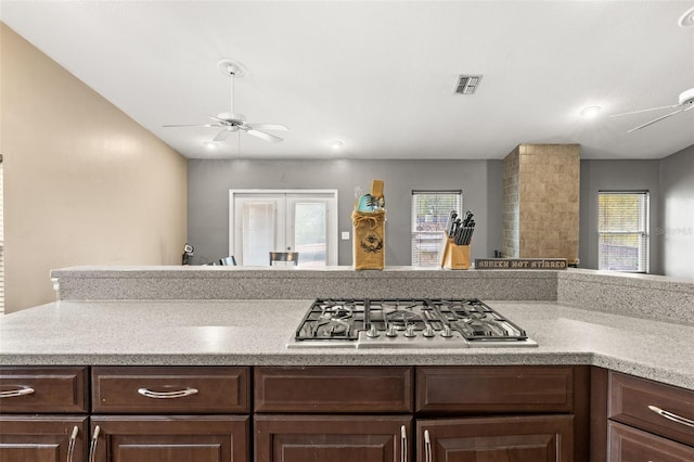 kitchen featuring stainless steel gas cooktop, a ceiling fan, dark brown cabinetry, and light countertops