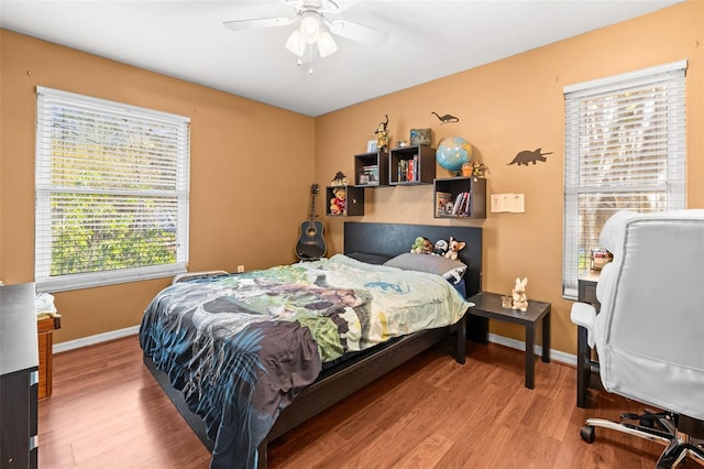 bedroom with wood finished floors, baseboards, and a ceiling fan