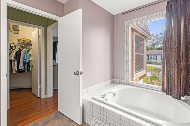 bathroom featuring a garden tub and a spacious closet