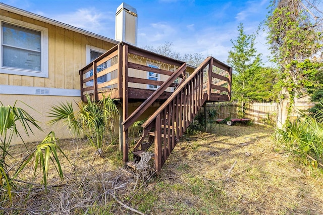 view of property exterior featuring a deck, stairway, and fence