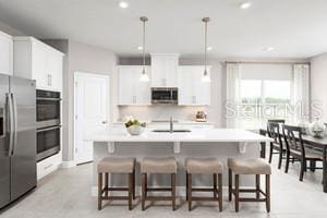 2193 Aibonito Cir, Clermont, FL 34711 - kitchen with appliances with stainless steel finishes, a kitchen breakfast bar, white cabinets, hanging light fixtures, and light countertops