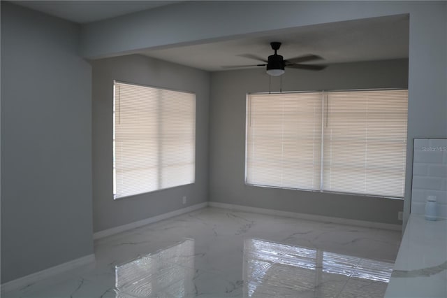 unfurnished room featuring marble look tiles, baseboards, and a ceiling fan