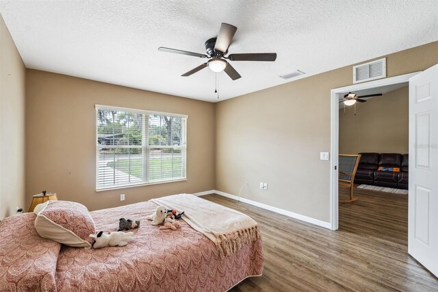 1161 Crk 443, Lake Panasoffkee, FL 33538 - bedroom featuring wood finished floors, a textured ceiling, baseboards, and ceiling fan