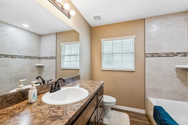1161 Crk 443, Lake Panasoffkee, FL 33538 - full bathroom featuring a tub, toilet, vanity, baseboards, and wood finished floors