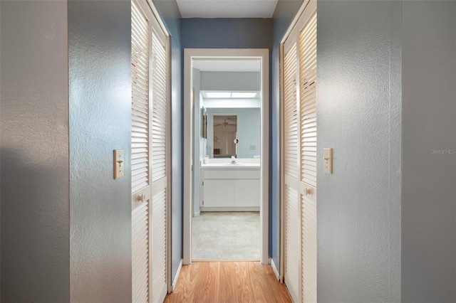 6490 Pine Meadows Dr, Spring Hill, FL 34606 - hallway with a textured wall, wood finished floors, baseboards, and a sink