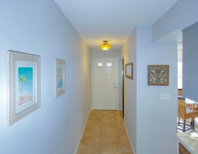 hall with baseboards, light tile patterned flooring, a textured ceiling, and plenty of natural light