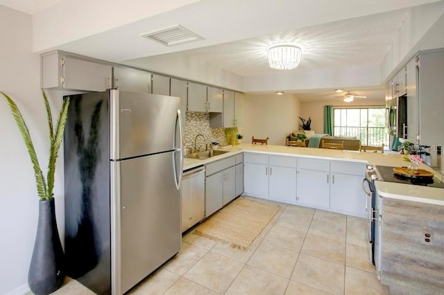 kitchen featuring stainless steel appliances, gray cabinets, a sink, light tile patterned flooring, and light countertops