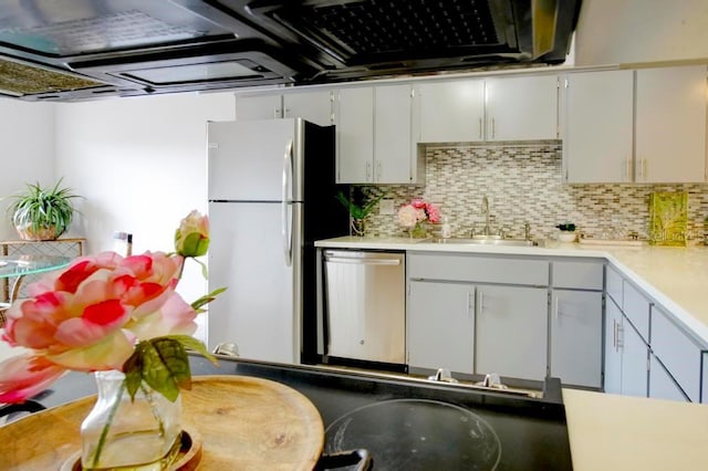 kitchen with dishwasher, freestanding refrigerator, a sink, backsplash, and light countertops