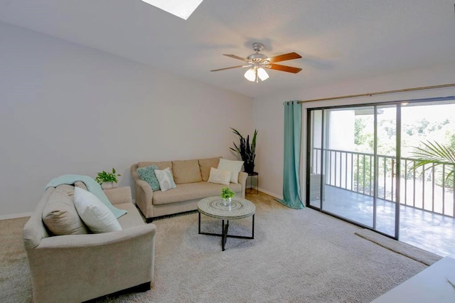 carpeted living area with a ceiling fan, a skylight, and baseboards