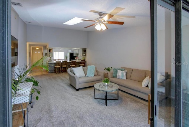living room featuring carpet, a skylight, and a ceiling fan