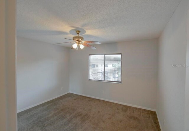 carpeted spare room featuring ceiling fan, a textured ceiling, and baseboards