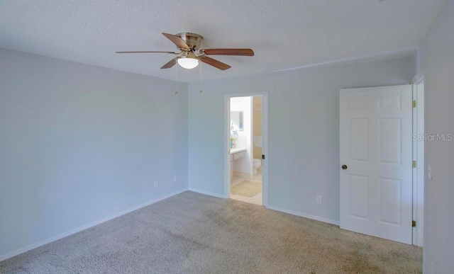 unfurnished bedroom with carpet, connected bathroom, baseboards, a ceiling fan, and a textured ceiling