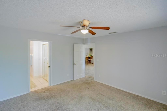 carpeted empty room featuring a ceiling fan, a textured ceiling, and baseboards