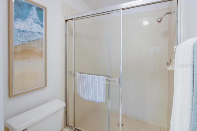 bathroom featuring toilet and a shower stall
