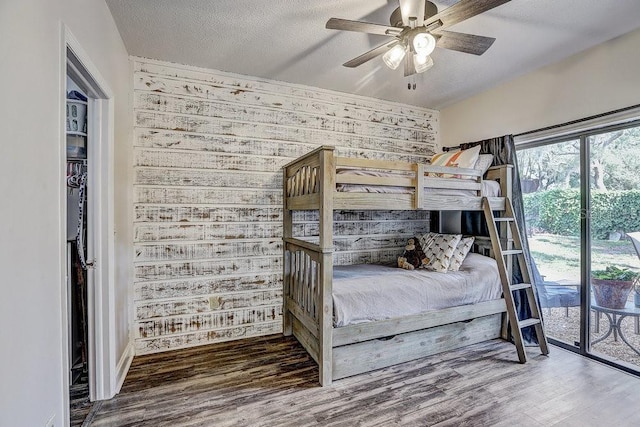 10910 Winter Oak Pl, Tampa, FL 33618 - bedroom with wood finished floors, wood walls, ceiling fan, access to outside, and a textured ceiling