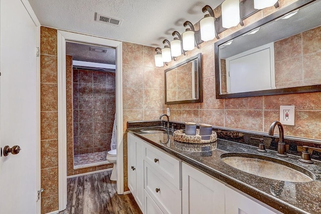 10910 Winter Oak Pl, Tampa, FL 33618 - full bathroom featuring a stall shower, toilet, wood finished floors, a textured ceiling, and double vanity