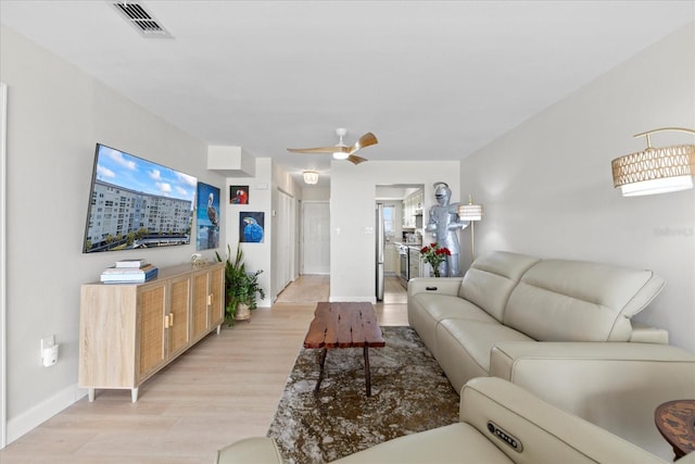 living area featuring light wood-style flooring, baseboards, and a ceiling fan
