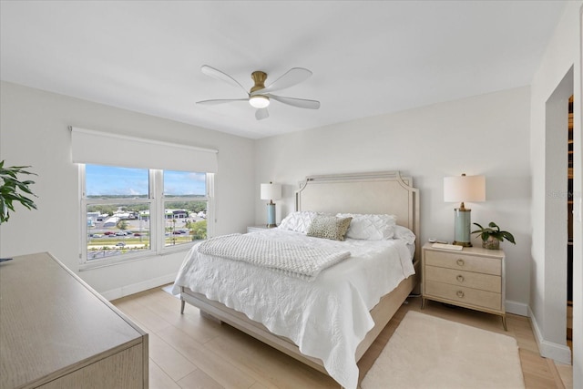 bedroom with light wood finished floors, ceiling fan, and baseboards