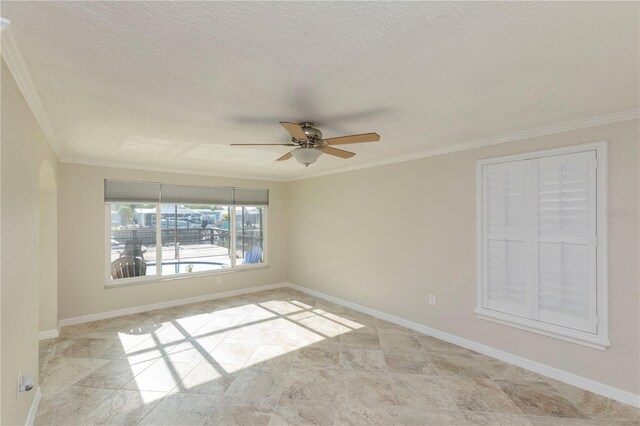 empty room with a ceiling fan, ornamental molding, a textured ceiling, baseboards, and stone finish floors