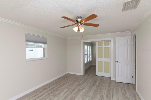 spare room with light wood-type flooring, ceiling fan, crown molding, a textured ceiling, and baseboards