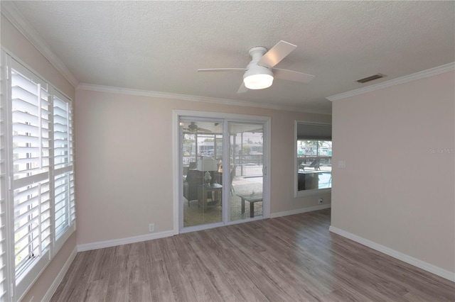 empty room featuring wood finished floors, a ceiling fan, a textured ceiling, crown molding, and baseboards