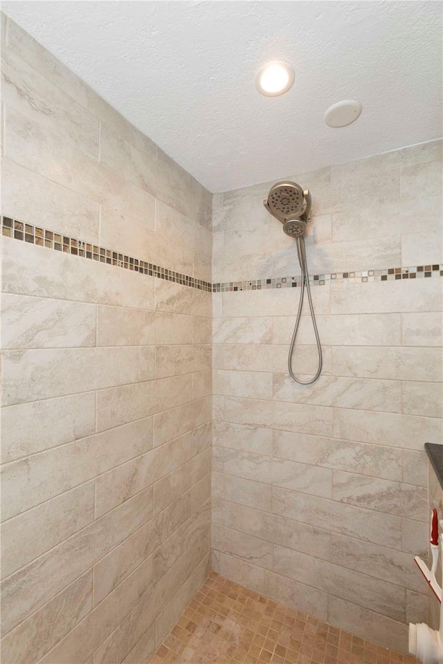 bathroom with tiled shower and a textured ceiling