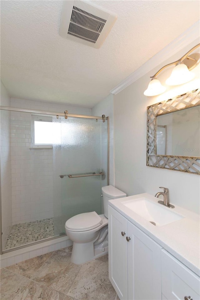 bathroom featuring a shower stall, toilet, a textured ceiling, and vanity