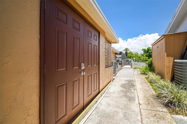 view of home's exterior with stucco siding, cooling unit, and a gate
