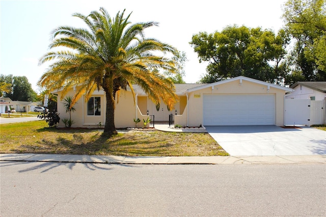 9200 Lunar Ln, Port Richey, FL 34668 - view of front of house featuring an attached garage, driveway, stucco siding, a gate, and fence