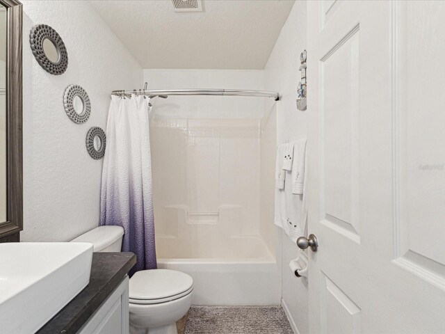 full bathroom with toilet, vanity, shower / bath combination with curtain, and a textured wall