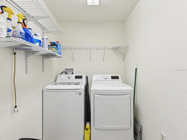 laundry room with washing machine and clothes dryer and a textured wall