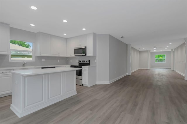 kitchen with stainless steel appliances, open floor plan, light countertops, plenty of natural light, and recessed lighting
