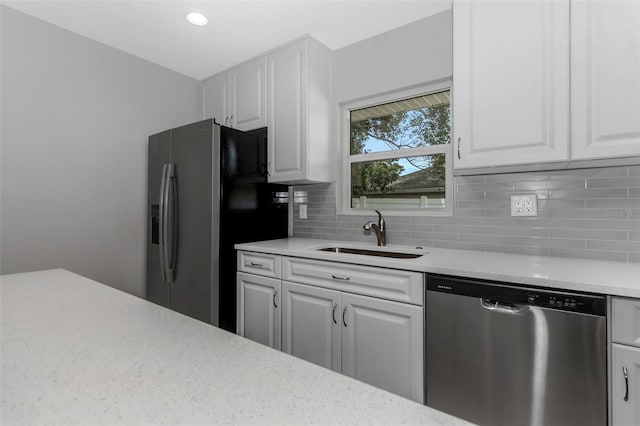 kitchen with stainless steel dishwasher, fridge with ice dispenser, a sink, decorative backsplash, and white cabinetry