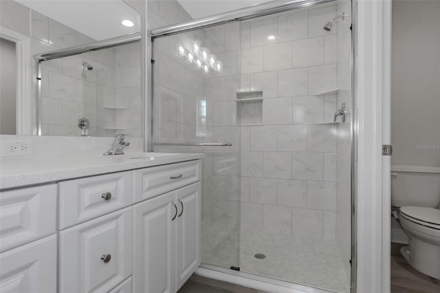 bathroom with toilet, a stall shower, and vanity
