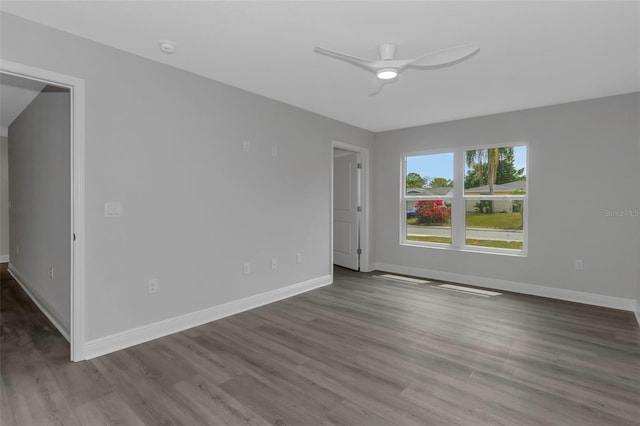 empty room featuring wood finished floors, baseboards, ceiling fan, and a smoke detector